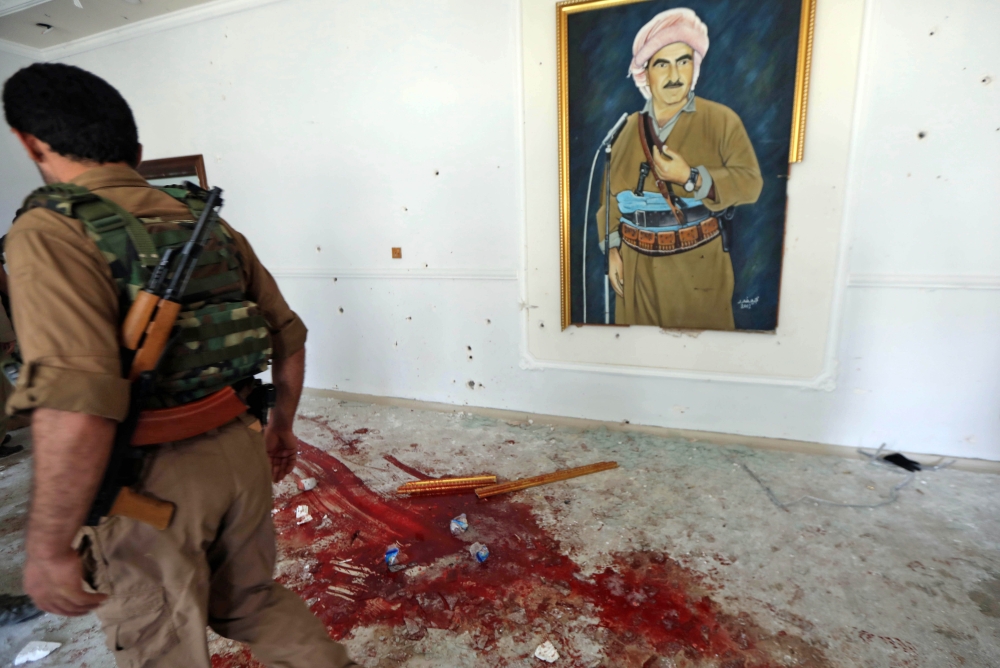 An official stands by blood strains at the Erbil governorate headquarters after an attack in Erbil, the capital of autonomous Iraqi Kurdistan on July 23, 2018. An official was killed on July 23 at the headquarters of the governorate of Erbil, capital of Iraqi Kurdistan, during an attack by three gunmen later shot dead by security forces, officials said. / AFP / SAFIN HAMED 