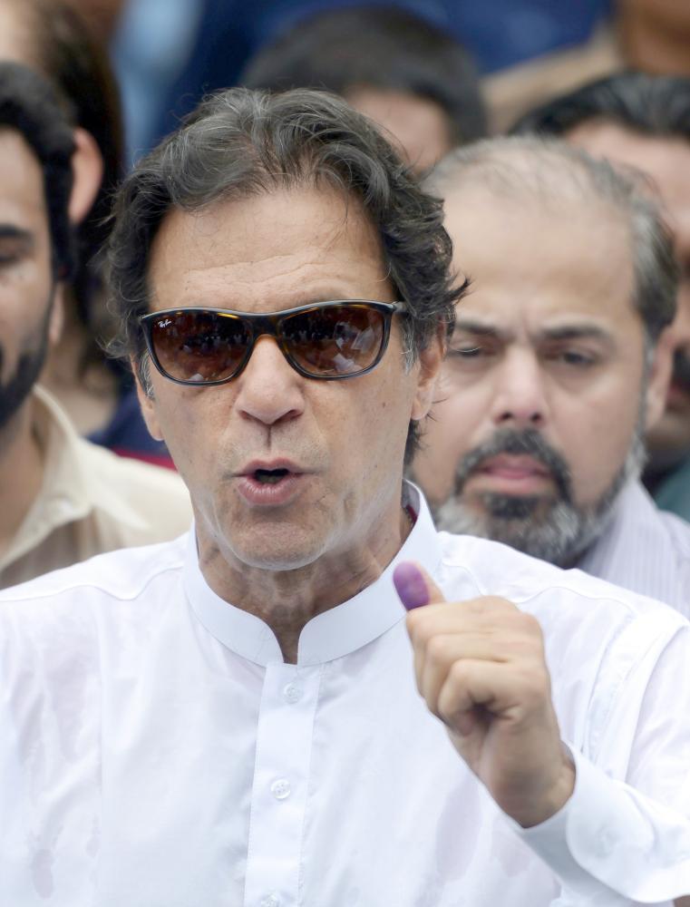 Pakistan's cricketer-turned politician Imran Khan of the Pakistan Tehreek-e-Insaf (Movement for Justice) speaks to the media after casting his vote at a polling station during the general election in Islamabad on July 25, 2018. Pakistanis voted July 25 in elections that could propel former World Cup cricketer Imran Khan to power, as security fears intensified with a voting-day blast that killed at least 30 after a campaign marred by claims of military interference. / AFP / AAMIR QURESHI
