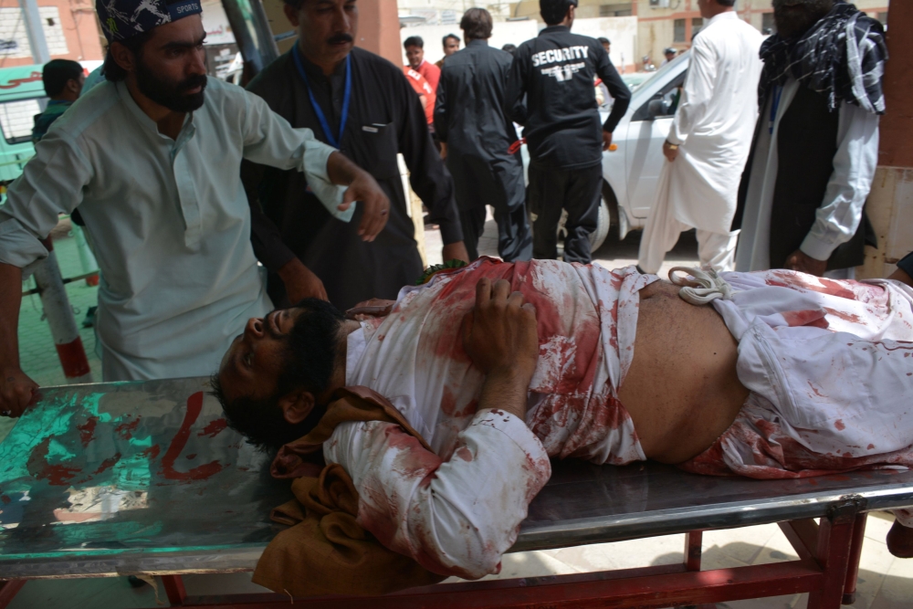 A Pakistani man pushes a stretcher carrying an injured blast victim at a hospital after a suicide attack near a polling station in Quetta on July 25, 2018. At least 30 people were killed and dozens more wounded in a suicide attack on a polling station in the southwestern Pakistani city of Quetta, officials said, as millions voted in a nationwide election on July 25. / AFP / BANARAS KHAN
