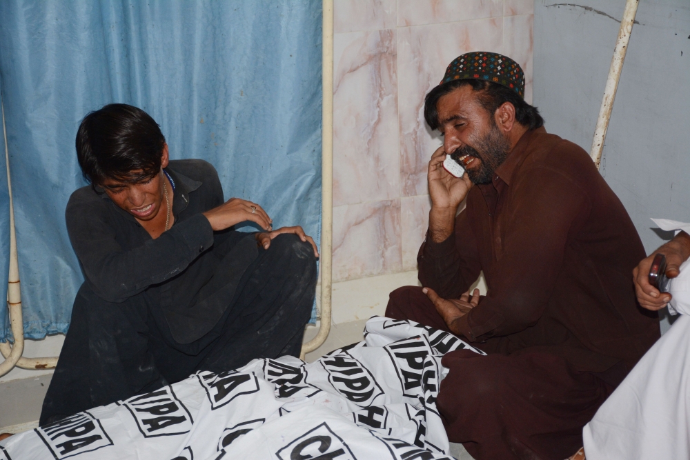 EDITORS NOTE: Graphic content / Pakistani relatives mourn beside the dead body of a blast victim at a hospital following a suicide attack near a polling station, at a hospital in Quetta on July 25, 2018. At least 30 people were killed and dozens more wounded in a suicide attack on a polling station in the southwestern Pakistani city of Quetta, officials said, as millions voted in a nationwide election on July 25. / AFP / BANARAS KHAN
