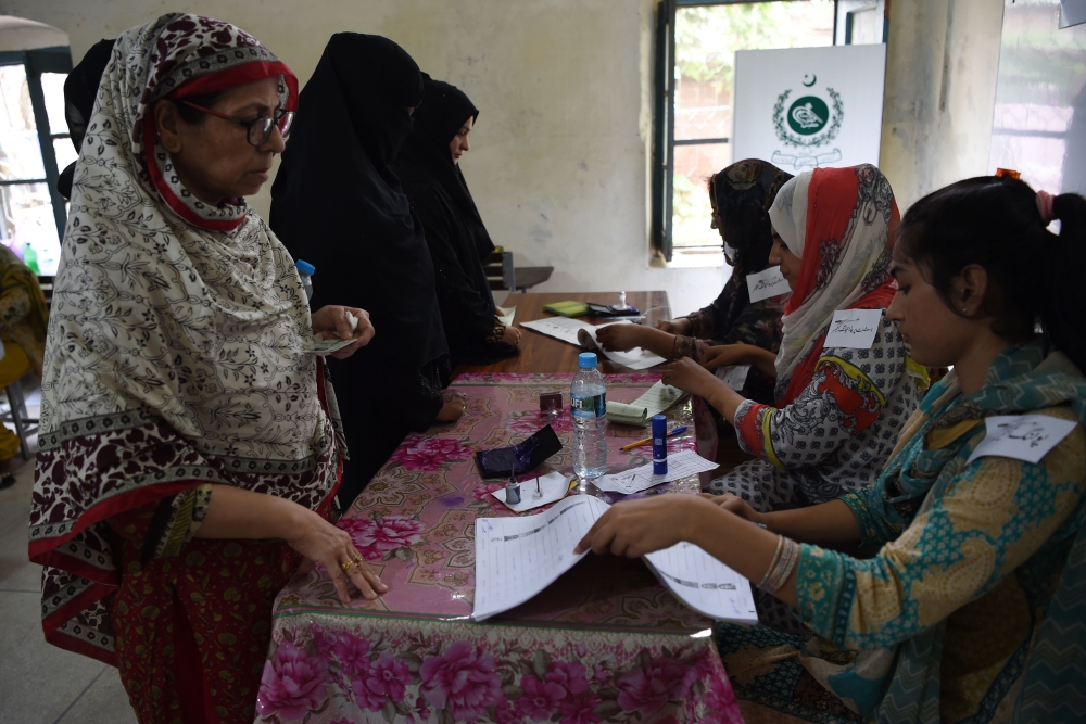Pakistani women voters wait to get their ballot papers to cast their votes during Pakistan's general election at a polling station in Lahore on July 25, 2018. Pakistanis voted July 25 in elections that could propel former World Cup cricketer Imran Khan to power, as security fears intensified with a voting-day blast that killed at least 28 after a campaign marred by claims of military interference.
 / AFP / WAKIL KOHSAR
