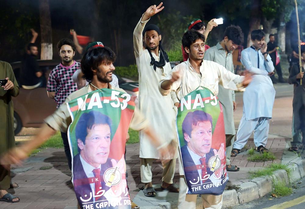 Supporters of Pakistan's cricketer-turned politician Imran Khan, head of the Pakistan Tehreek-e-Insaf (Movement for Justice) party, celebrate on a street during general election in Islamabad on July 25, 2018.

 Pakistan's incumbent party rejected early election results Thursday that suggested former cricket hero Imran Khan was on his way to becoming the country's next prime minister, alleging «blatant» rigging. 

 / AFP / AAMIR QURESHI
