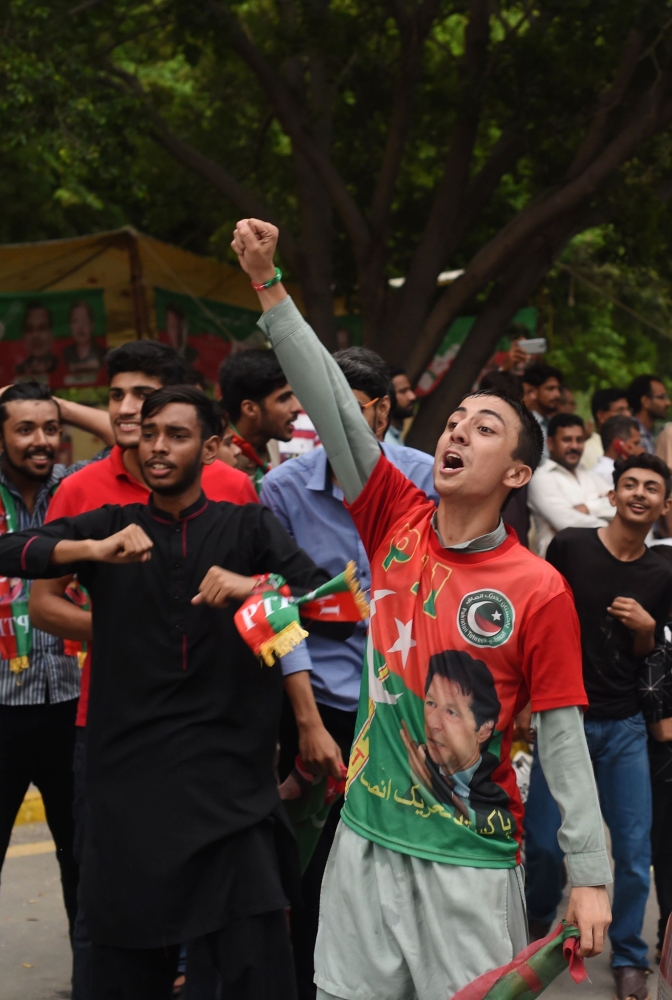 Supporters of Pakistani cricket star-turned-politician and head of the Pakistan Tehreek-e-Insaf (PTI) Imran Khan cheer as they take to the street to celebrate after polls closed during Pakistan's general election, in Lahore on July 25, 2018. Vote-counting began on July 25 in a knife-edge Pakistan general election as former cricket hero Imran Khan sought power on a day marred by a bloody suicide bombing and claims of military interference. / AFP / WAKIL KOHSAR
