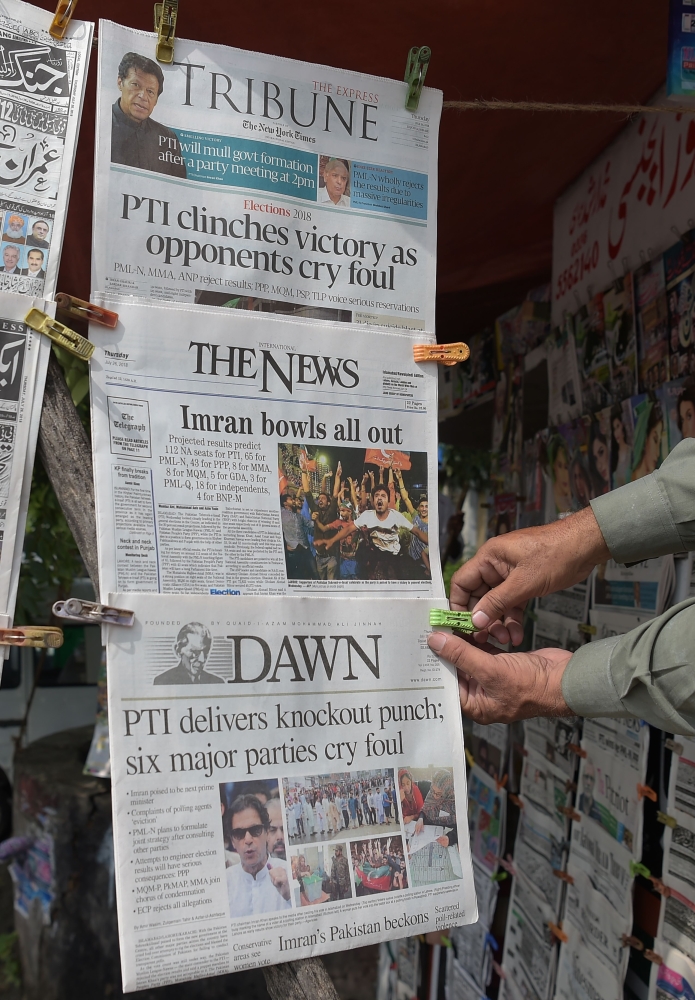 A Pakistani vendor arranges morning newspapers at a stall a day after the general election in Islamabad on July 26, 2018. Pakistan woke to electoral chaos on July 26 with the outgoing ruling party denouncing 