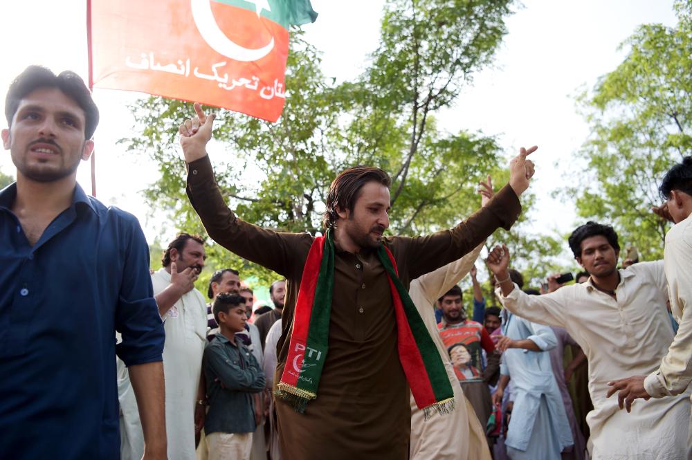 Supporters of Pakistan's cricketer-turned politician and head of the Pakistan Tehreek-e-Insaf (Movement for Justice) party Imran Khan dance as they celebrate near his residence in Islamabad on July 26, 2018 a day after general election. Pakistan cricket hero turned politician Imran Khan claimed victory on July 26 in the country's tense general election marred by allegations of 