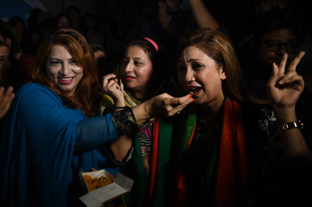 Supporters of Pakistan's cricketer-turned politician Imran Khan, and head of the Pakistan Tehreek-e-Insaf (Movement for Justice) party, eat sweets as they celebrate in Karachi on July 26, 2018, a day after a general election.

 Pakistan cricket hero turned politician Imran Khan has claimed victory on July 26, in the country's tense general election marred by allegations of «blatant» rigging by rival parties. A visibly tired Khan cut a conciliatory tone in a wide-ranging address to the nation following a controversial contest hit by accusations from major political parties of poll rigging and long delays in still unreleased official results. / AFP / RIZWAN TABASSUM
