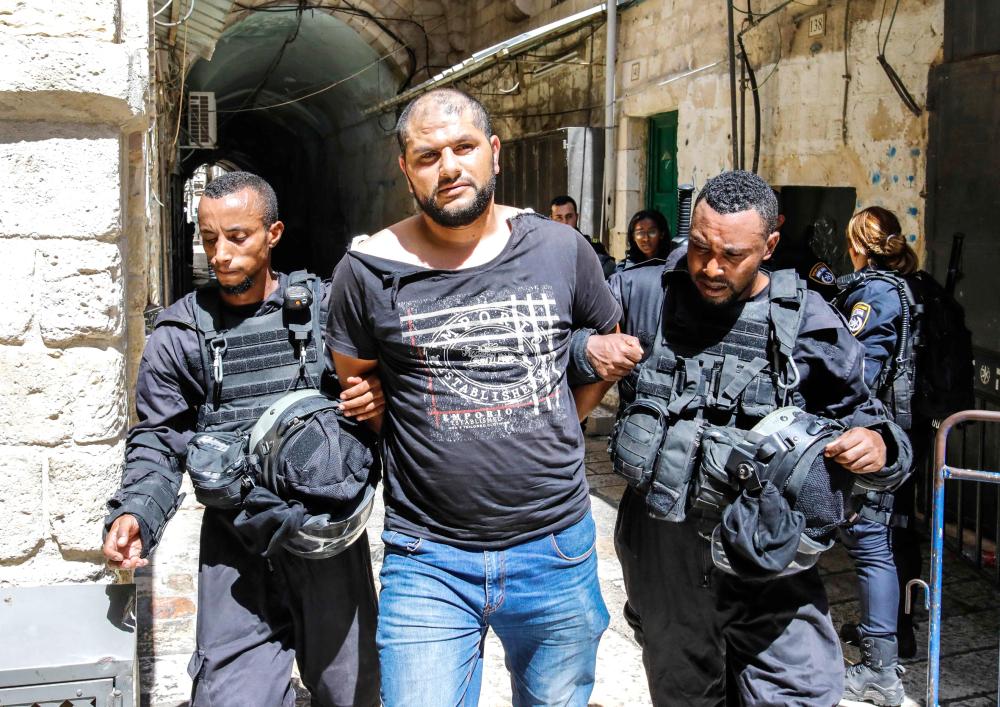 Members of the Israeli security forces take into custody a Palestinian protester who was arrested during clashes at the Aqsa mosque compound in the Old City of Jerusalem on July 27, 2018. / AFP / Ahmad GHARABLI
