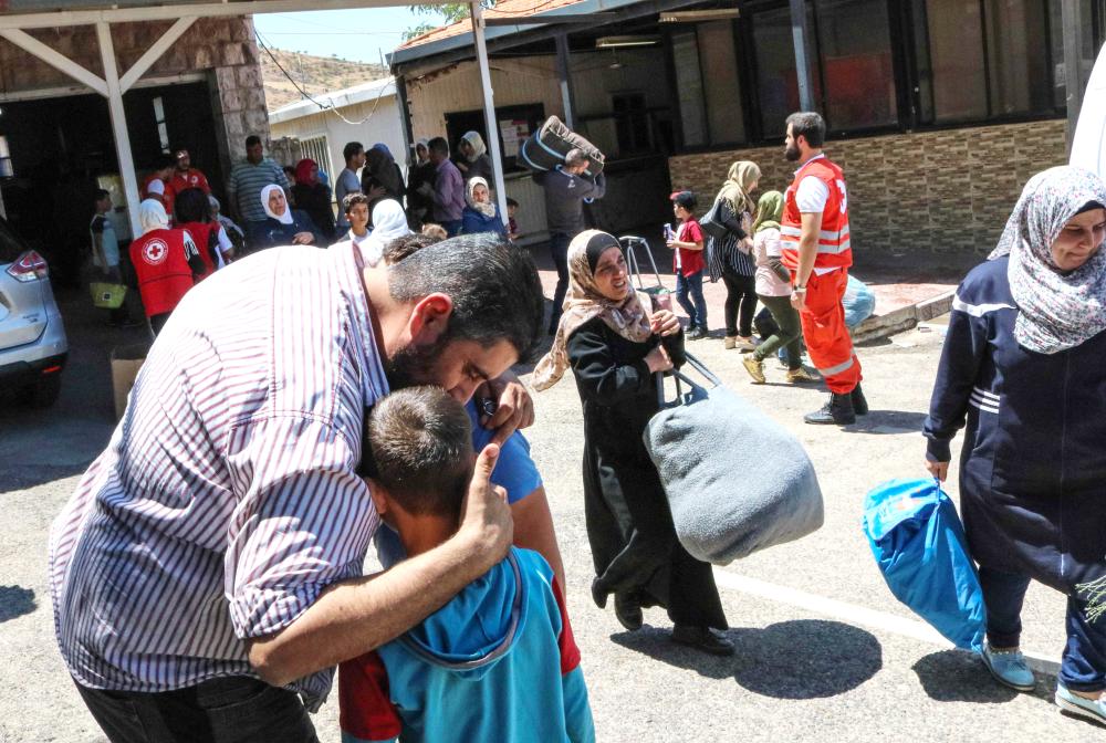 



سوري يواسي طفلين من اللاجئين العائدين إلى سورية عند معبر على الحدود بين البلدين أمس.  (أ ف ب)