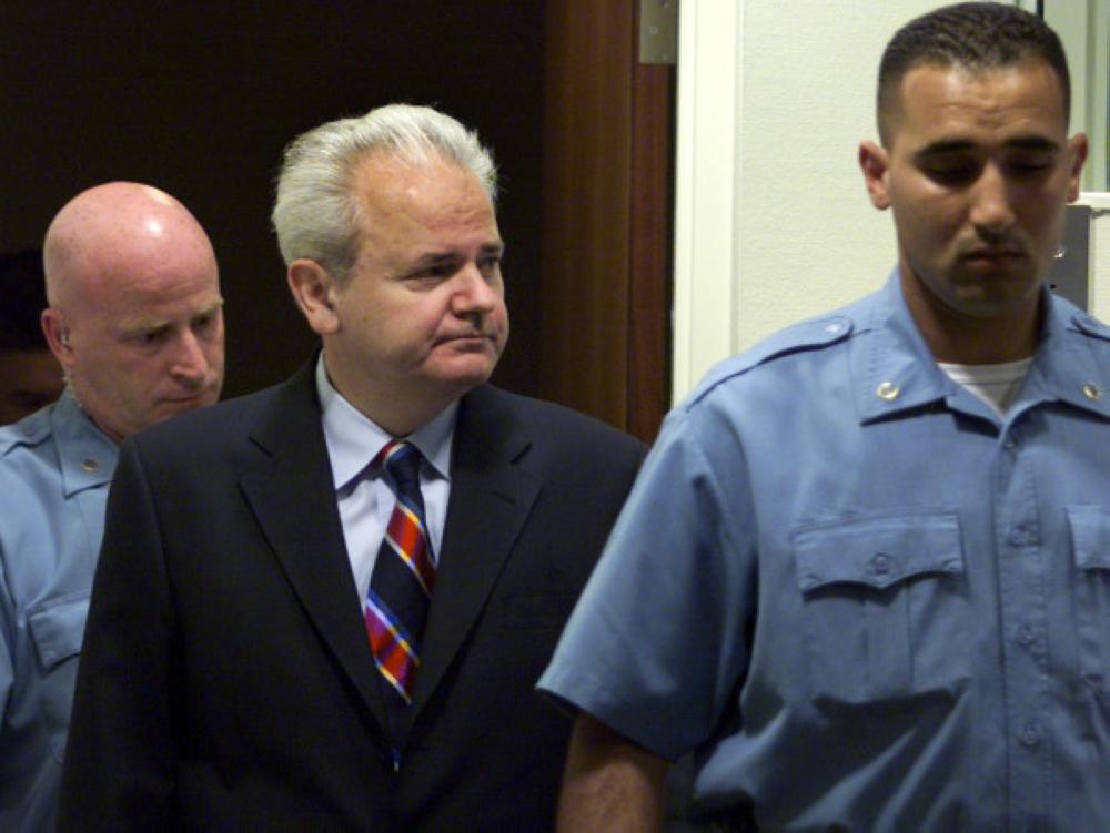 


Former Yugoslav President Slobodan Milosevic is escorted into the courtroom by a United Nations security officer as he makes his initial appearance at the War Crimes Tribunal for the former Yugoslavia in The Hague July 3, 2001. Milosevic refused to plead to the war crimes charges against him at the International Criminal Tribunal for former Yugoslavia on Tuesday, and the judge said a «not guilty» plea would be entered on his behalf.