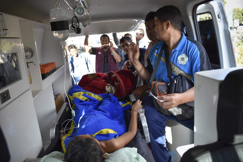 Members of an Indonesian medical team transport an earthquake survivor in an ambulance in Lombok on July 29, 2018. A powerful earthquake which struck the Indonesian tourist island of Lombok on July 29 killed at least 14 people, injured scores and damaged thousands of homes, officials said. / AFP / AULIA AHMAD
