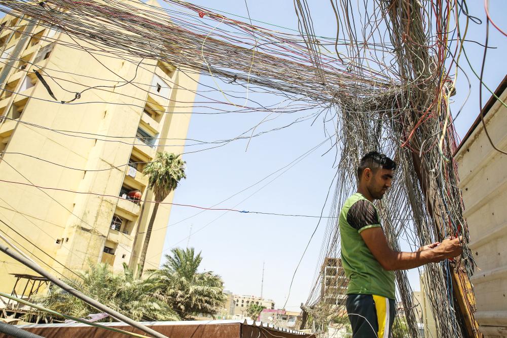 



 عراقي يتفحص الأسلاك في كابلات كهربائية تصل إلى المنازل في شارع السعدون ببغداد أمس. (أ.ف.ب)