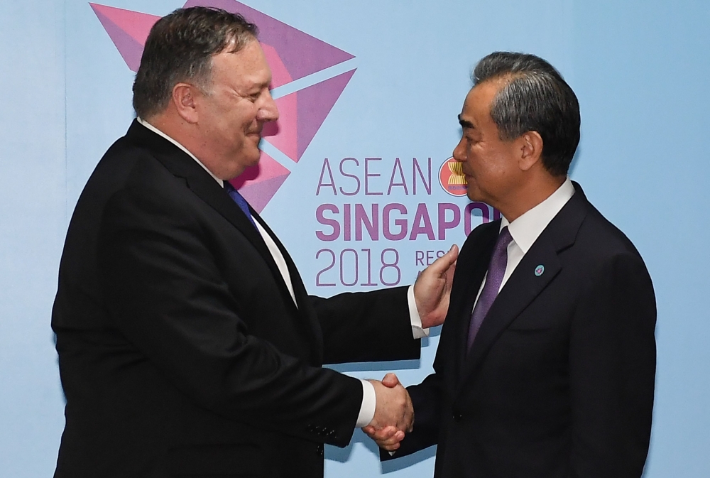 US Secretary of State Mike Pompeo (L) and China's Foreign Minister Wang Yi (R) shake hands before their bilateral meeting at the 51st Association of Southeast Asian Nations (ASEAN) in Singapore on August 3, 2018. Leaders, ministers and representatives are meeting in the city-state from August 1 to 4 for the ASEAN Ministerial Meeting (AMM). / AFP / POOL / MOHD RASFAN
