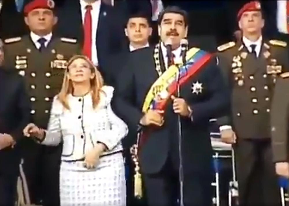 Screengrab taken from a handout video released by Venezuelan Television (VTV) showing Venezuelan President Nicolas Maduro (C), his wife Cilia Flores (L) and military authorities reacting to a loud band during a ceremony to celebrate the 81st anniversary of the National Guard in Caracas on August 4, 2018. Maduro was unharmed after an exploding drone 