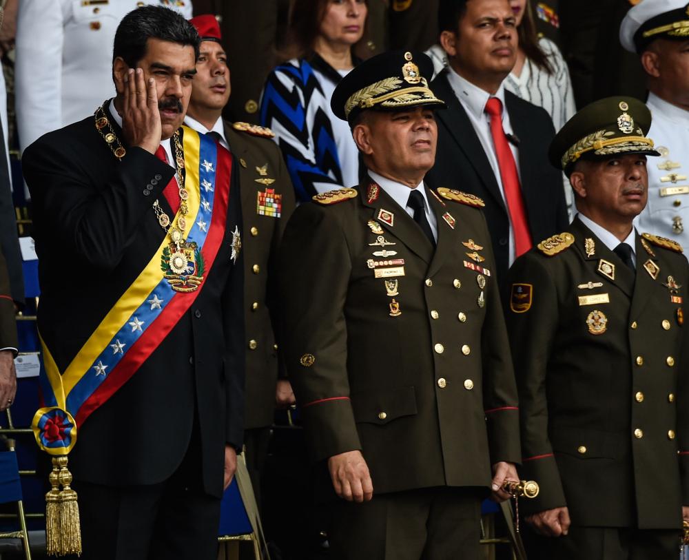 TOPSHOT - Venezuelan President Nicolas Maduro (L) gestures next to Minister of Defence General Vladimir Padrino (C), during a ceremony to celebrate the 81st anniversary of the National Guard in Caracas on August 4, 2018. Maduro was unharmed after an exploding drone 