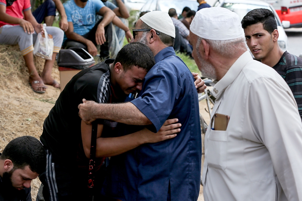 Palestinian relatives of Ahmad Murjan, the young Hamas fighter killed by Israeli fire, mourn over his death during the funeral in Jabalia, in the northern Gaza Strip, on August 7, 2018. Israeli forces on August 7 killed two militants of the Gaza Strip's ruling Hamas movement, the health ministry in the Palestinian territory said. Hamas's military wing, the Ezzedine al-Qassam Brigades, confirmed in a statement that the dead men were its fighters and named them as Ahmed Murjan and Abdel-Hafez al-Silawi. Palestinian sources said that the Israeli attack was in the north of the strip but they said it was a drone strike, while the Israeli statement said that it was tank fire. / AFP / MAHMUD HAMS
