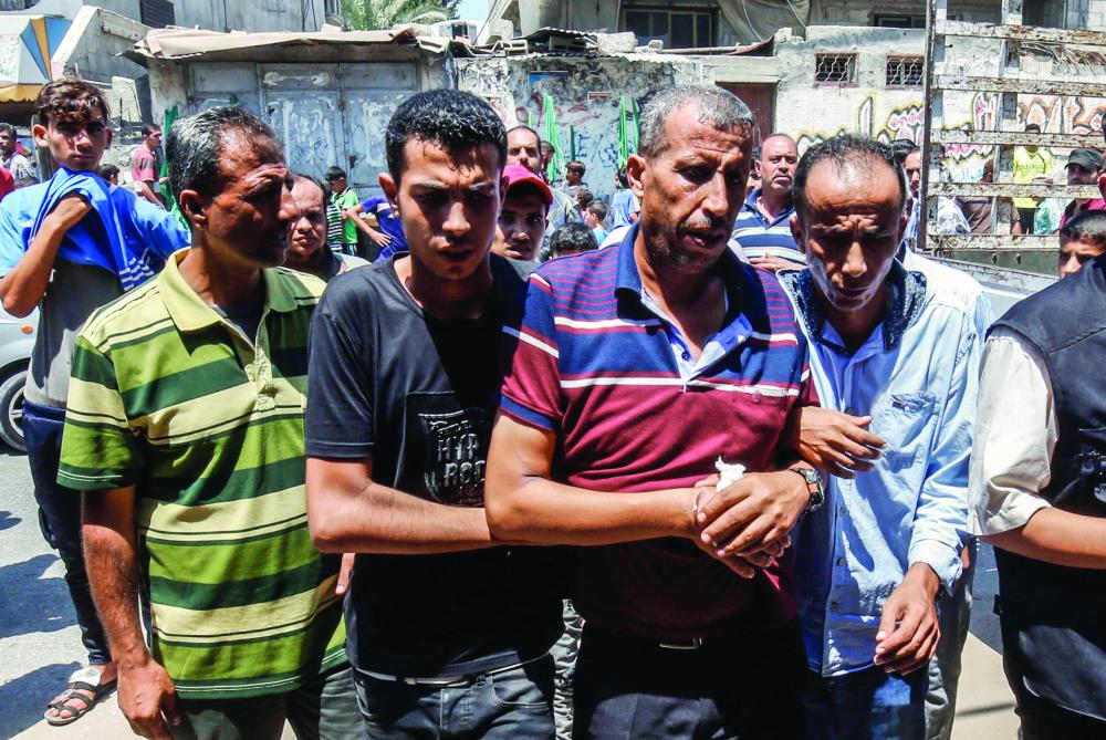 Palestinian mourners assist the father (2nd-R) of killed 23-year-old Enas Khammash walk during her and her daughter's funeral in Deir Al-Balah in the central Gaza Strip on August 9, 2018 who were killed earlier in an Israeli airstrike. The the Hamas-controlled enclave's health ministry had reported earlier that the pregnant mother and her child were killed and the husband injured.Israel struck a series of sites in retaliation for dozens of rockets fired early on August 9. / AFP / SAID KHATIB
