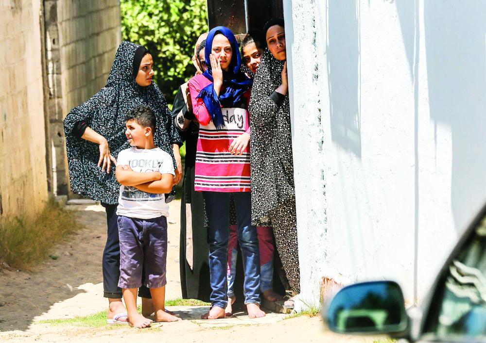 Palestinian women and children watch as the funerary procession of 30-year-old Hamas fighter Ali Ghandour passes by in Beit Lahya in the northern Gaza Strip on August 9, 2018 after he was killed by Israeli shelling late the previous night. Israel struck a series of sites in Gaza in response to dozens of rockets fired from the Palestinian coastal enclave. / AFP / MAHMUD HAMS
