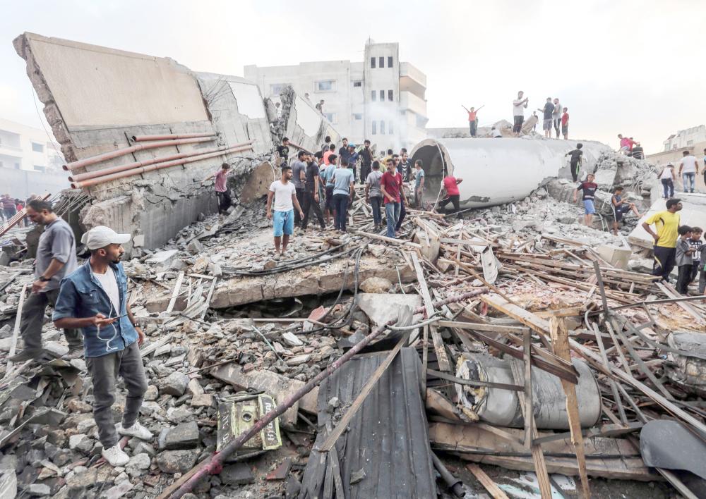 A picture taken on August 9, 2018 people inspecting the rubble of a building following an Israeli air strike on Gaza City. At least 18 Palestinians were wounded as Israel struck a building in central Gaza City, the health ministry in the Palestinian enclave said, after hours of relative calm. The strike hit a building that Palestinians say housed a cultural centre and other offices in the middle of the city, an AFP correspondent said. Israel's military had not commented. / AFP / MAHMUD HAMS
