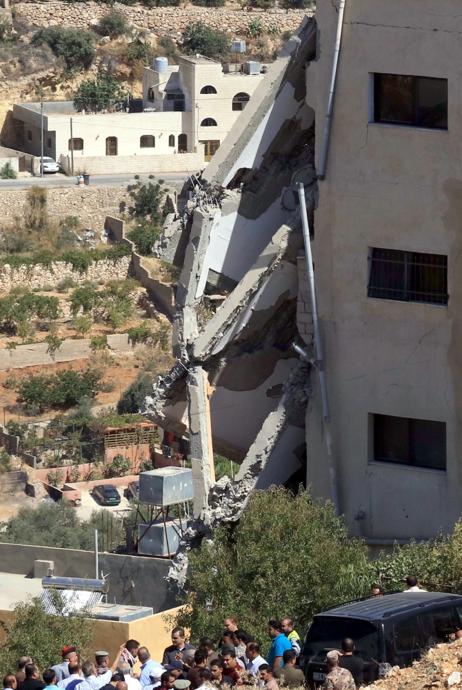 Jordanian security forces gather near a damaged building during a raid in the city of Salt, northwest of the capital Amman, on August 12, 2018. Jordanian security forces have killed three «terrorists» and arrested five others during a raid after an officer was killed in a bomb blast near the capital, the government said. Three members of the security forces also died in Saturday's raid, which came after the home-made bomb exploded under a patrol car at a music festival.
 / AFP / Khalil MAZRAAWI
