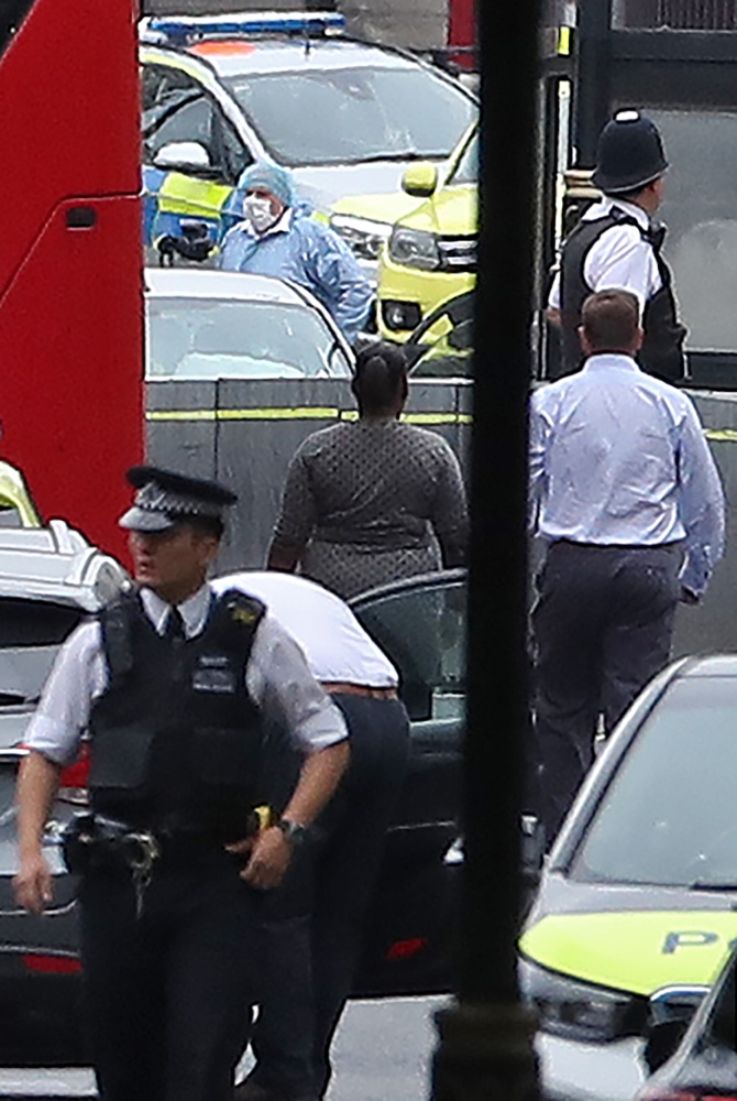 Police forensics officers work at the scene (top) outside the Houses of Parliament in central London on August 14, 2018, where a car was driven into the barriers. A «number of pedestrians» were injured when a car crashed into barriers outside Britain's Houses of Parliament today, with armed police swooping in to arrest the driver, Scotland Yard said. / AFP / Daniel LEAL-OLIVAS
