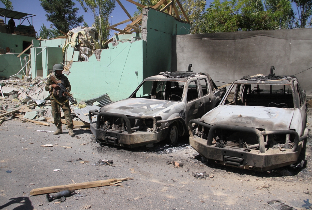 A member of the Afghan security forces stands guard next to damaged army vehicles after a Taliban attack in Ghazni city, Afghanistan August 15, 2018. REUTERS/Mustafa Andaleb