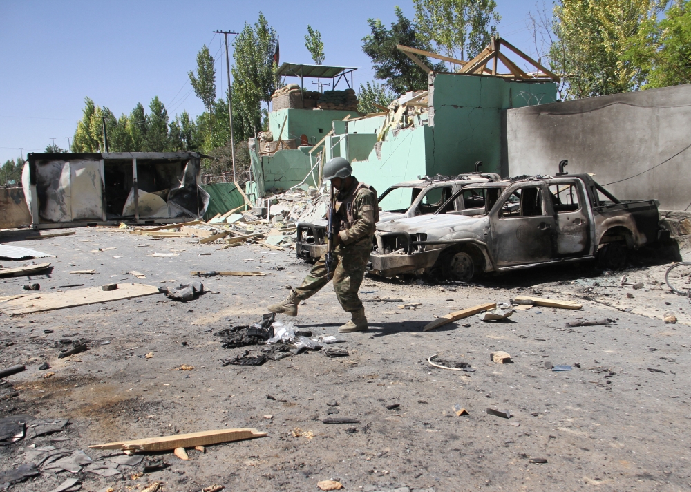 A member of the Afghan security forces stands guard next to damaged army vehicles after a Taliban attack in Ghazni city, Afghanistan August 15, 2018. REUTERS/Mustafa Andaleb