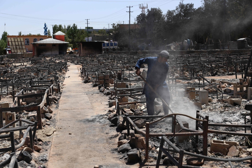 Afghan man shovels off debris after Taliban burned a market in the city of Ghazni on August 14, 2018. Afghan forces appeared to have finally pushed Taliban fighters from the strategic city of Ghazni on August 15, as shopkeepers and residents warily returned to the streets after days of intense ground fighting and US airstrikes. / AFP / ZAKERIA HASHIMI
