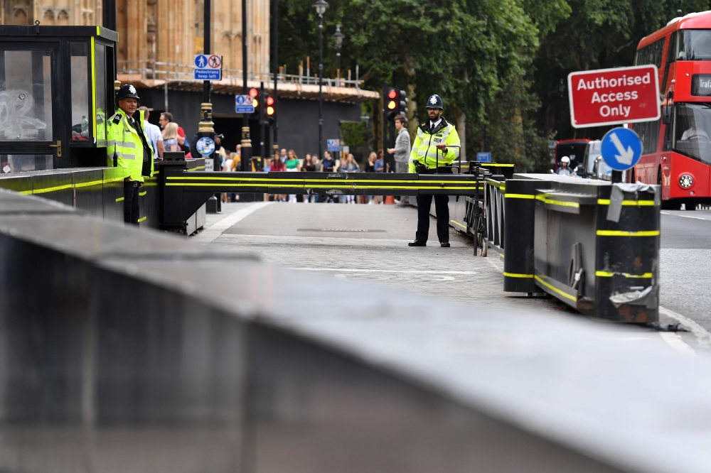 Police officers are seen at a traffic barrier outside the Houses of Parliament in central London on August 15, 2018 at the scene of a suspected terror attack on August 14.  The man arrested for driving into a barrier protecting the Houses of Parliament in a suspected terror attack was a Briton of Sudanese origin from Birmingham, media reports said on August 15. Three people were injured when the silver Ford Fiesta drove into cyclists before crashing to a halt outside the House of Lords early on Tuesday morning.
 / AFP / BEN STANSALL
