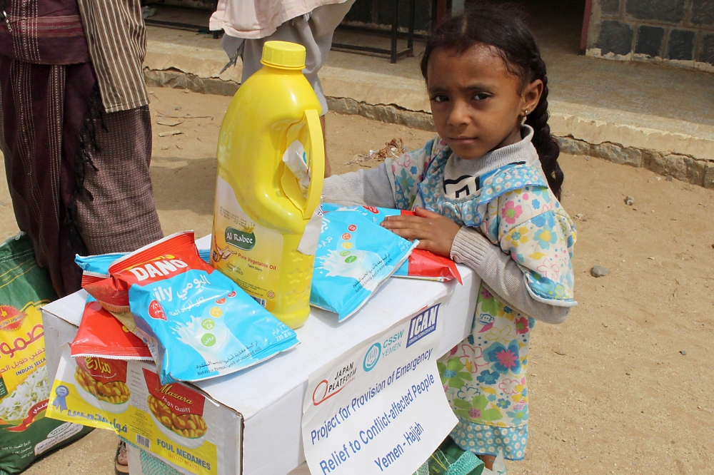 This picture taken on August 15, 2018 shows a displaced Yemeni child from Hodeida receiving food aid from a Japanese NGO in the northern district of Abs, in Hajjah province. / AFP / ESSA AHMED
