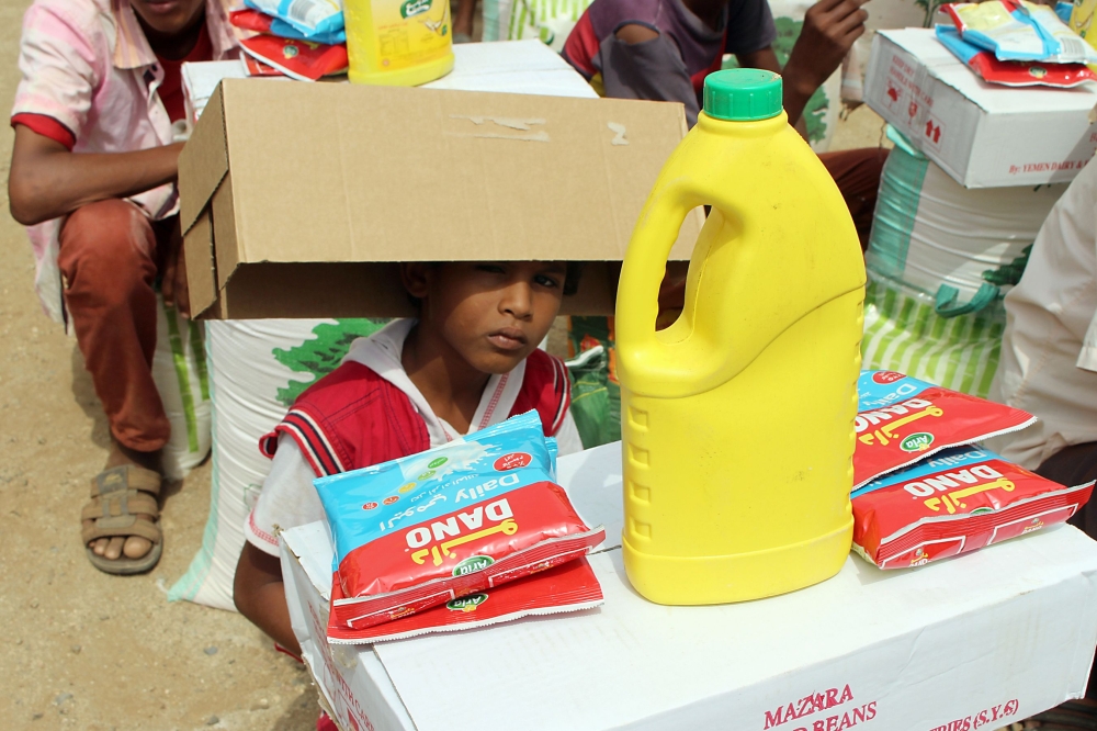 This picture taken on August 15, 2018 shows a displaced Yemeni child from Hodeida receiving food aid from a Japanese NGO in the northern district of Abs, in Hajjah province. / AFP / ESSA AHMED
