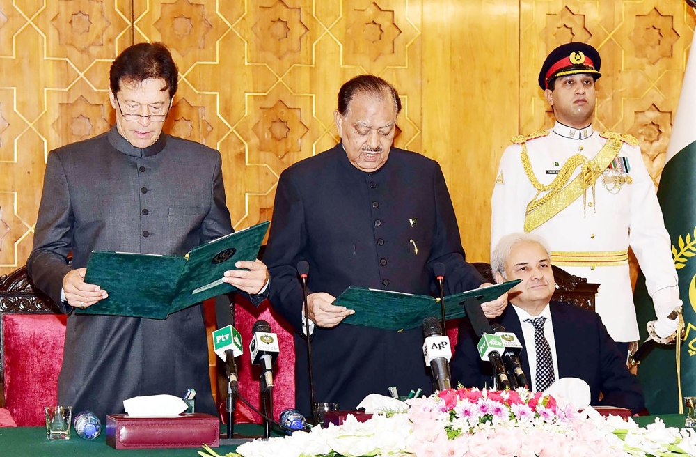 In this handout photograph released by Pakistan's Press Information Department (PID) on August 18, 2018, President of Pakistan Mamnoon Hussain (C) takes an oath from newly appointed Prime Minister Imran Khan (L) during a ceremony in Islamabad, as caretaker Prime Minister of Pakistan Nasirul Mulk (2R) looks on. Pakistan's new Prime Minister Imran Khan was sworn in at a ceremony in Islamabad on August 18, ushering in a new political era as the World Cup cricket hero officially took the reins of power in the nuclear-armed country. - RESTRICTED TO EDITORIAL USE - MANDATORY CREDIT «AFP PHOTO / PID» - NO MARKETING NO ADVERTISING CAMPAIGNS - DISTRIBUTED AS A SERVICE TO CLIENTS -
 / AFP / PID / Handout / RESTRICTED TO EDITORIAL USE - MANDATORY CREDIT «AFP PHOTO / PID» - NO MARKETING NO ADVERTISING CAMPAIGNS - DISTRIBUTED AS A SERVICE TO CLIENTS -
