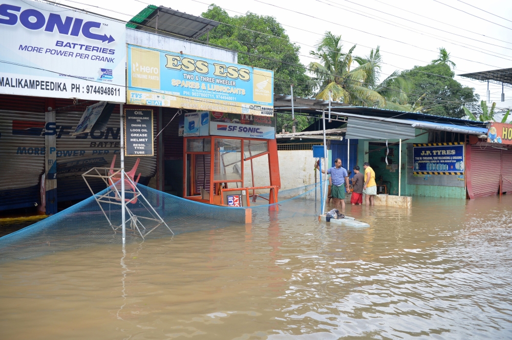 People wade through gradually receding flood waters in Paravur on the outskirts of Kochi in the south Indian state of Kerala, on August 20, 2018. Receding flood waters left Indian troops and rescuers the grim task August 20 of hunting for bodies left by the worst monsoon in a century in Kerala state as the death toll rose above 400. / AFP / MANJUNATH KIRAN
