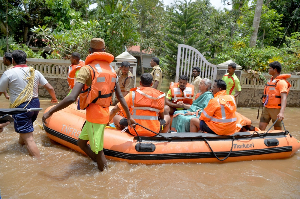 Kerala and Tamil Nadu Fire Force personnel ferry children and eldery in a dinghy through flood waters during a rescue operation in Annamanada village in Thrissur District, in the south Indian state of Kerala, on August 19, 2018. Rescuers waded into submerged villages in southern India on August 19 in a desperate search for survivors cut off for days by floods that have already killed more than 350 people.
 / AFP / MANJUNATH KIRAN
