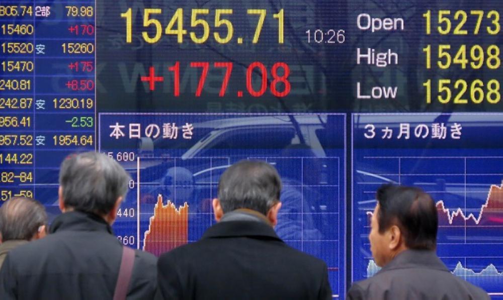 Pedestrians walk in front of a quotation board displaying the Nikkei key index of the Tokyo Stock Exchange in Tokyo on December 18, 2013.  Tokyo stocks opened flat on December 18 as investors await the US Federal Reserve's decision on whether to begin scaling back its huge stimulus.  AFP PHOTO / KAZUHIRO NOGI
