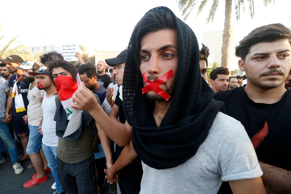 Iraqis with tape on their mouths attend a protest in the southern city of Basra on August 24, 2018. Iraq has been gripped by protests over power outages, unemployment, state mismanagement and a lack of clean water. The demonstrations erupted in the neglected southern province of Basra, home to Iraq's only sea port, before spreading north including to Baghdad. / AFP / Haidar MOHAMMED ALI
