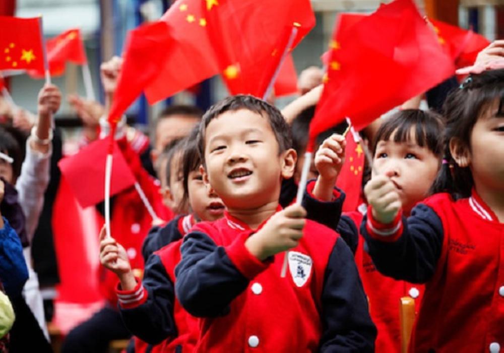 Children wave national flags as they sing revolutionary songs to celebrate the upcoming National Day at a kindergarten in Tonglu in China's eastern Zhejiang province on September 29, 2017. / AFP PHOTO / STR / China OUT (Photo credit should read STR/AFP/Getty Images)