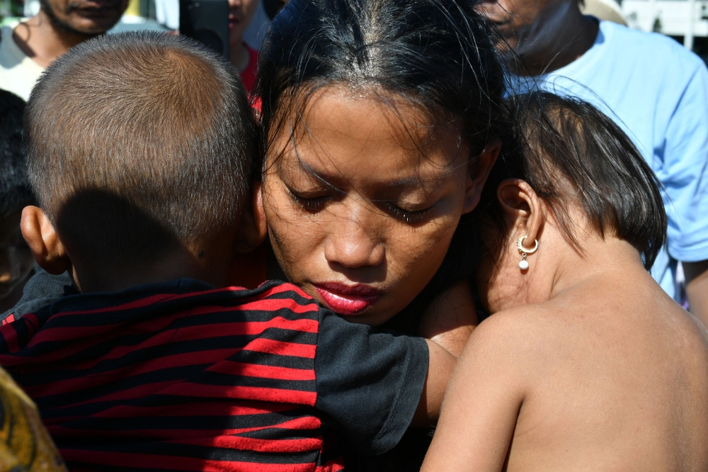 TOPSHOT - Susi Rahmatia, 26, holds her second child (R) and Jumadil (L), 5, after he went missing for seven days following the earthquake and tsunami, at a shelter in Palu on October 5, 2018. Susi Rahmatia thought her five-year-old son Jumadil was dead, but on Friday -- a week after they were separated by Indonesia's earthquake and tsunami – they enjoyed a miraculous and emotional reunion. / AFP / ADEK BERRY 