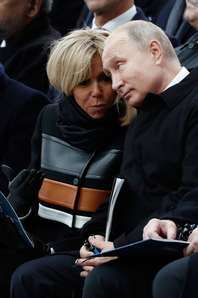 French President's wife Brigitte Macron (L) and Russian President Vladimir Putin (R) speak together as they attend a ceremony at the Arc de Triomphe in Paris on November 11, 2018 as part of commemorations marking the 100th anniversary of the 11 November 1918 armistice, ending World War I. / AFP / POOL / BENOIT TESSIER
