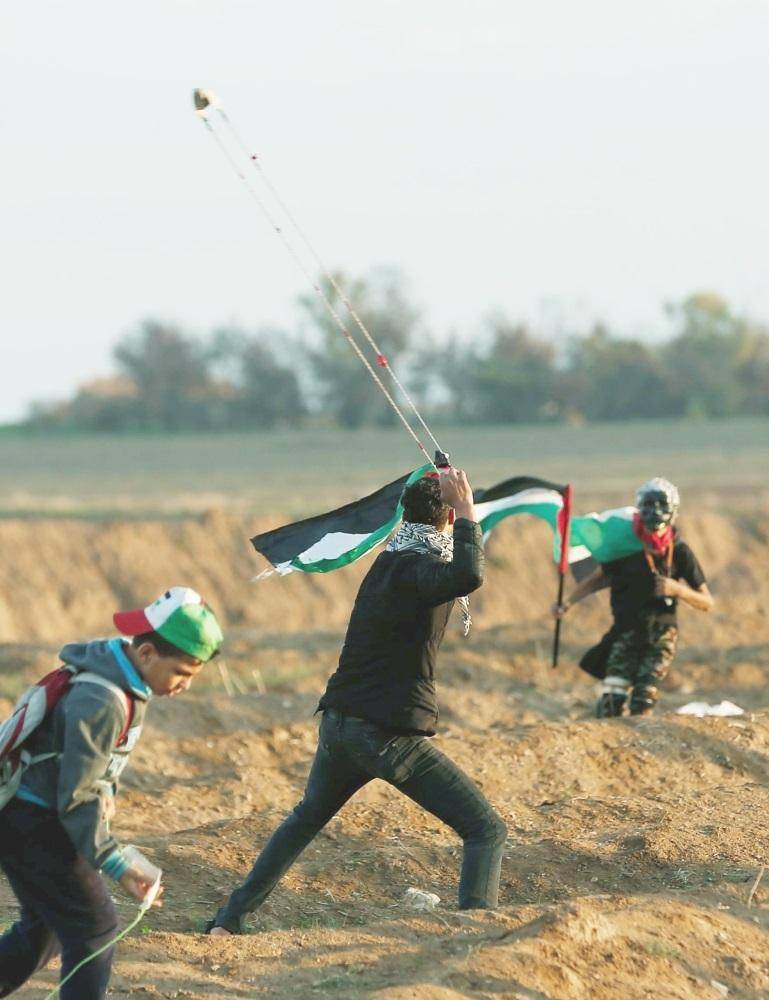 فلسطيني يرمي قوات الاحتلال بالحجارة خلال اشتباكات على الحدود بين غزة وإسرائيل أمس الأول. (أ ف ب)