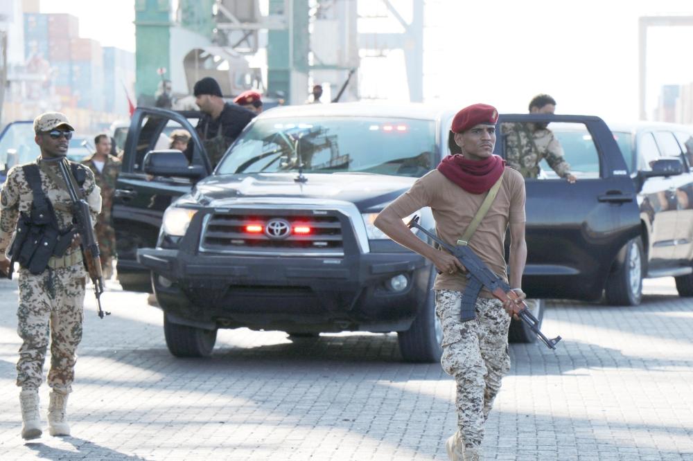 جنود يرافقون مسؤولين حكوميين يقومون بجولة في محطة الحاويات في ميناء عدن (رويترز)
