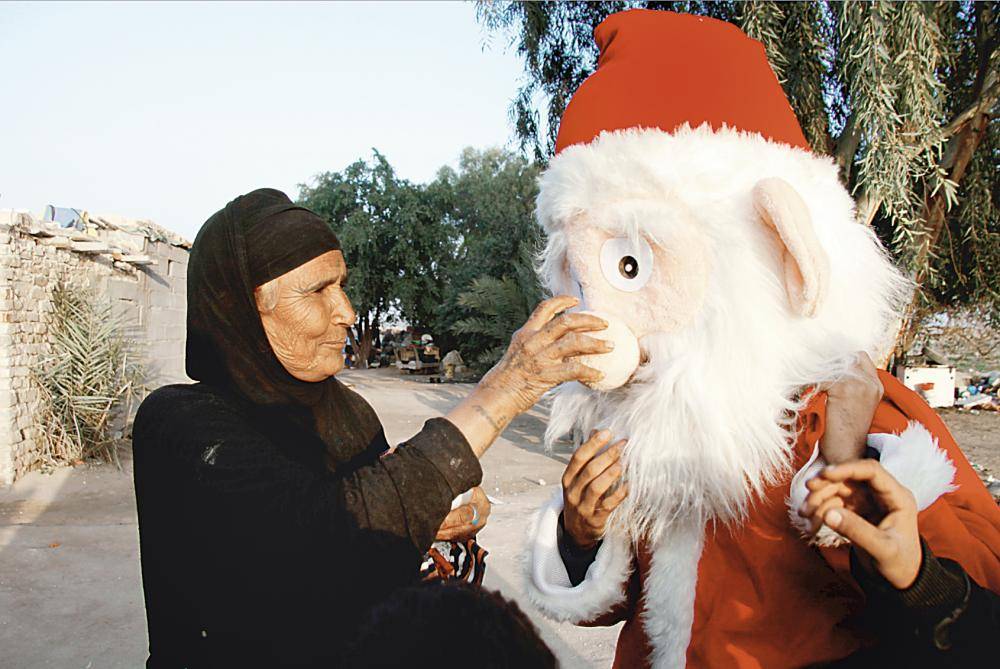 مسنة عراقية تروي ظمأ بابا نويل. (أ. ف. ب)