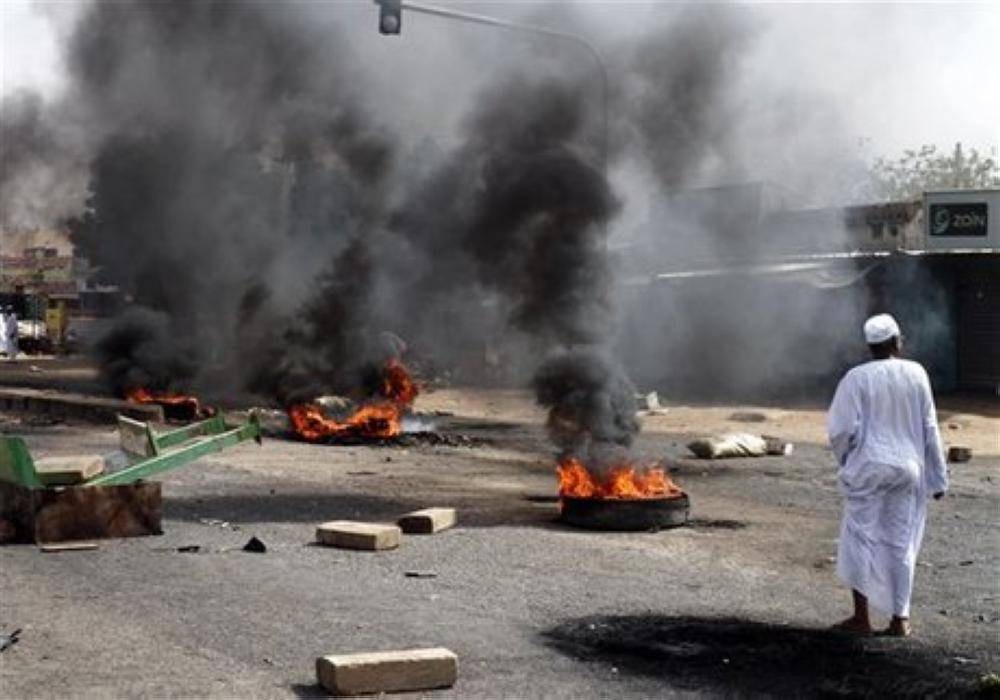 A Sudanese man looks at tires burnt by protesters to close the highway to northern cities amid a wave of unrest over the lifting of fuel subsidies by the Sudanese government, in Kadro, 15 miles (24.14 kilometers) north of downtown Khartoum, Wednesday, Sept. 25, 2013. Sudan's loss of its main oil-producing territory with the independence of South Sudan in 2011 was a punch to its fragile economy. (AP Photo/Abd Raouf)