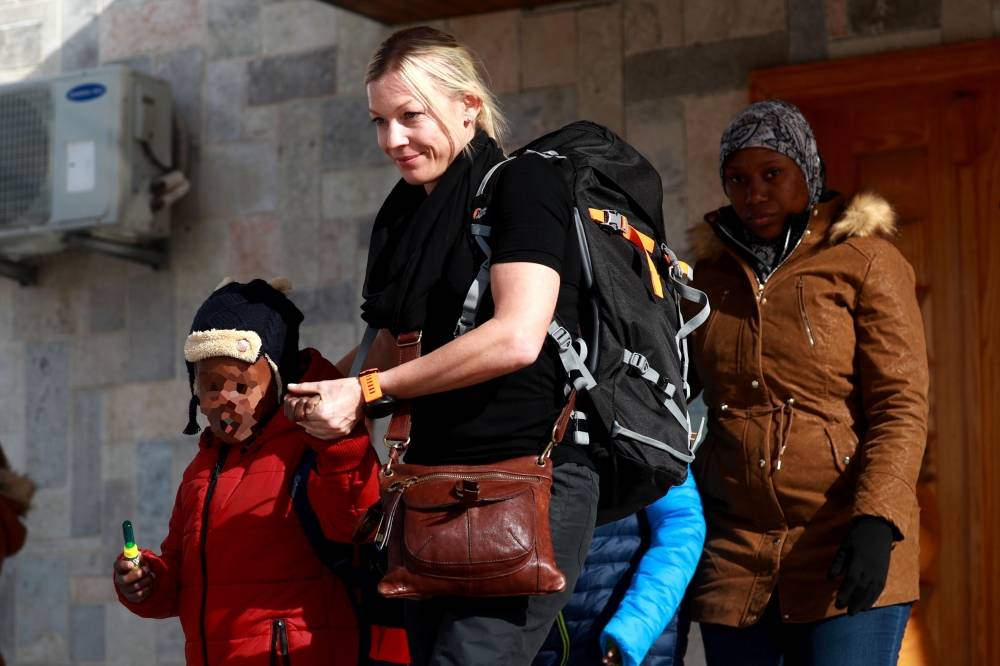 A member of an NGO accompanies two Caribbean children and their mother (R) as they prepare to leave the northeastern Syrian Kurdish-majority city of Qamishli on January 21, 2018. Syria's Kurds handed two children from Trinidad and Tobago to their mother today, four years after their jihadist father brought them to the Islamic State group's «caliphate», a lawyer said.
Ayyub Ferreira, 7, and his brother Mahmud, 11, were to leave Syria after Pink Floyd singer Roger Waters helped fly their mother to meet them, lawyer and rights activist Clive Stafford-Smith said. / AFP / Delil SOULEIMAN
