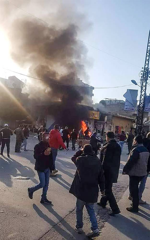 This handout image made available by the official Syrian Arab News Agency (SANA)'s Telegram page on January 22, 2019, shows people gathering around a burning vehicle in the Syrian regime's coastal stronghold of Latakia. A car bomb exploded today in Latakia, killing one person and wounding four others, state news agency SANA reported. 