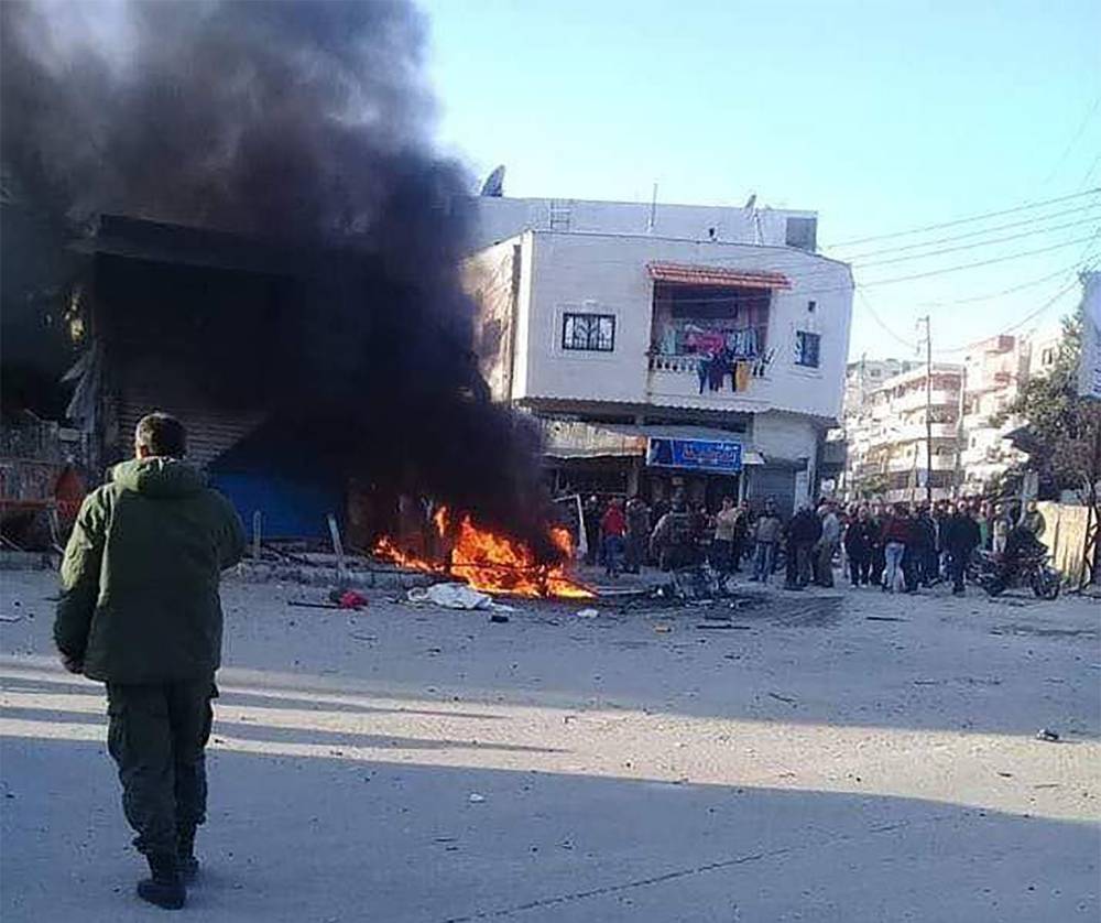 This handout image made available by the official Syrian Arab News Agency (SANA)'s Telegram page on January 22, 2019, shows people gathering around a burning vehicle in the Syrian regime's coastal stronghold of Latakia. A car bomb exploded today in Latakia, killing one person and wounding four others, state news agency SANA reported. 