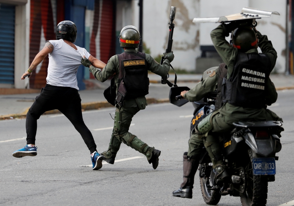 FILE PHOTO: Security forces run after a demonstrator during a protest of opposition supporters against Venezuelan President Nicolas Maduro's government in Caracas, Venezuela January 23, 2019. REUTERS/Carlos Garcia Rawlins/File Photo