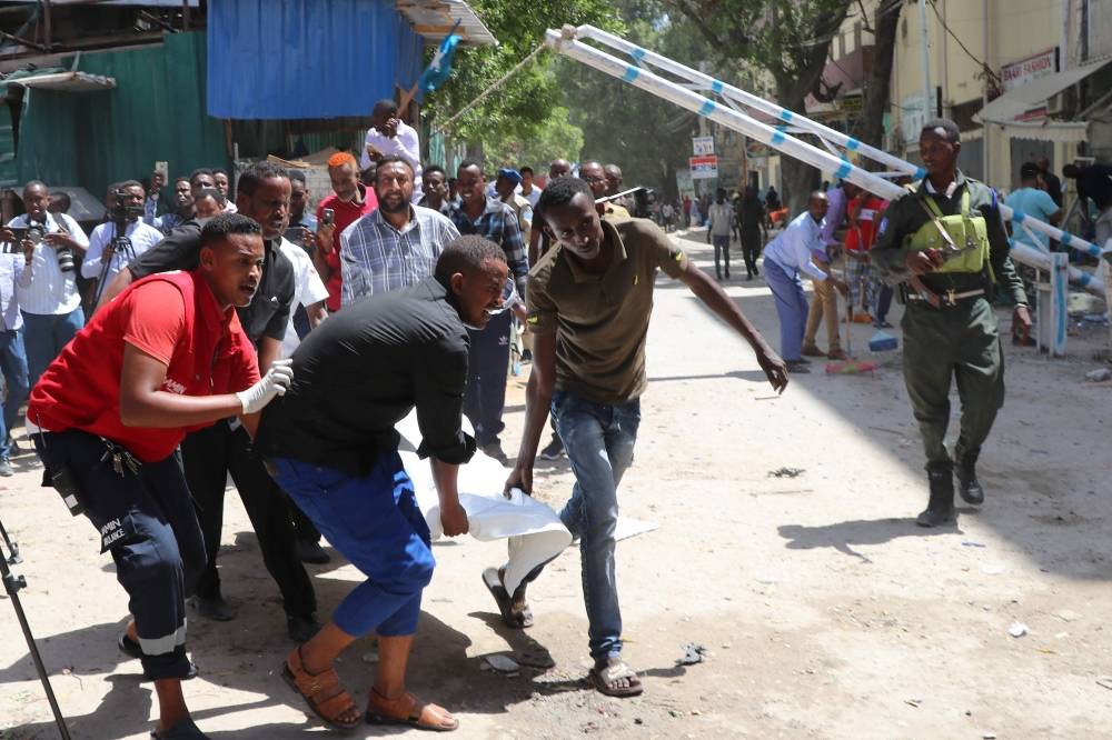 Emergency rescue staff and volunteers carry the body of a victim from the scene of a car-bomb attack on February 4, 2019 in Somalia capital Mogadishu's Hamarwayne District. At least nine people were killed and several wounded when a car loaded with explosives blew up near a mall in a busy market in the Somali capital on Monday, police said. / AFP / ABDIRAZAK HUSSEIN FARAH 