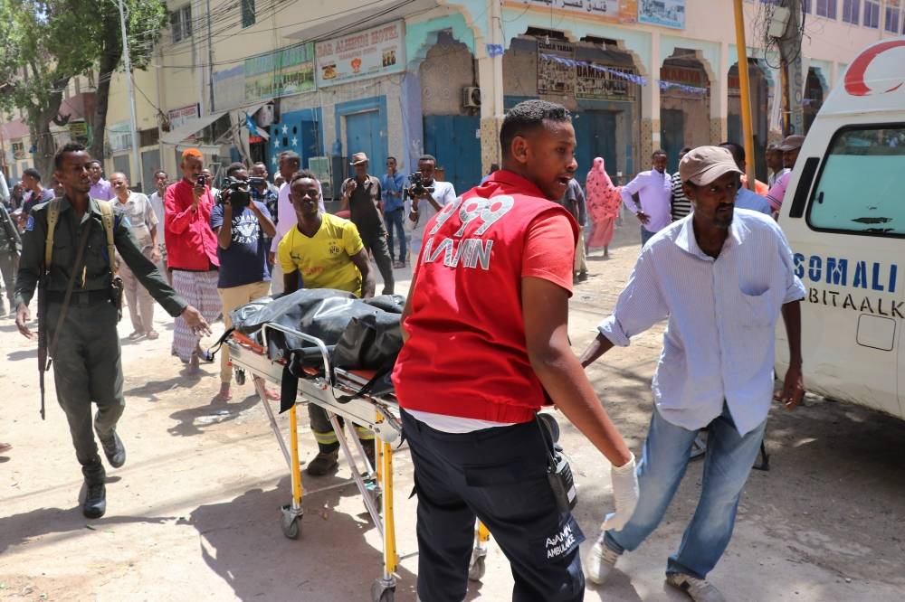 Emergency rescue staff carry the body of a victim on a gurney at the scene of a car-bomb attack on February 4, 2019 in Somalia capital Mogadishu's Hamarwayne District. At least nine people were killed and several wounded when a car loaded with explosives blew up near a mall in a busy market in the Somali capital on Monday, police said. / AFP / ABDIRAZAK HUSSEIN FARAH 