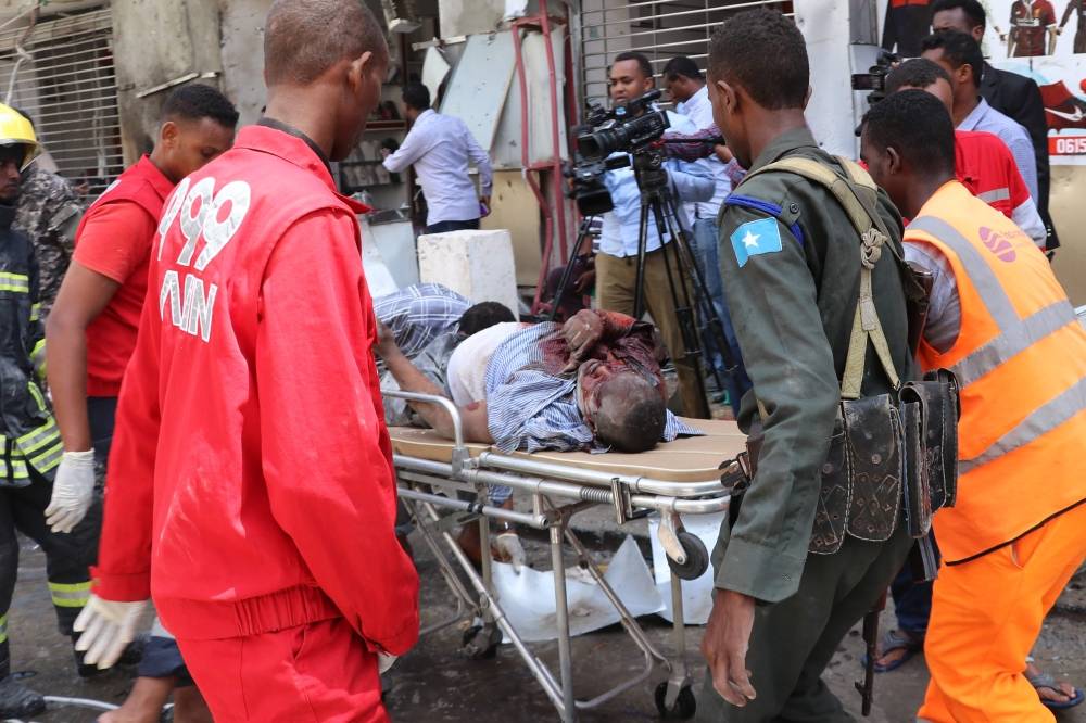 EDITORS NOTE: Graphic content / Emergency rescue staff carry a man with head injuries at the scene of a car-bomb attack on February 4, 2019 in Somalia capital Mogadishu's Hamarwayne District. At least nine people were killed and several wounded when a car loaded with explosives blew up near a mall in a busy market in the Somali capital on Monday, police said. / AFP / ABDIRAZAK HUSSEIN FARAH 