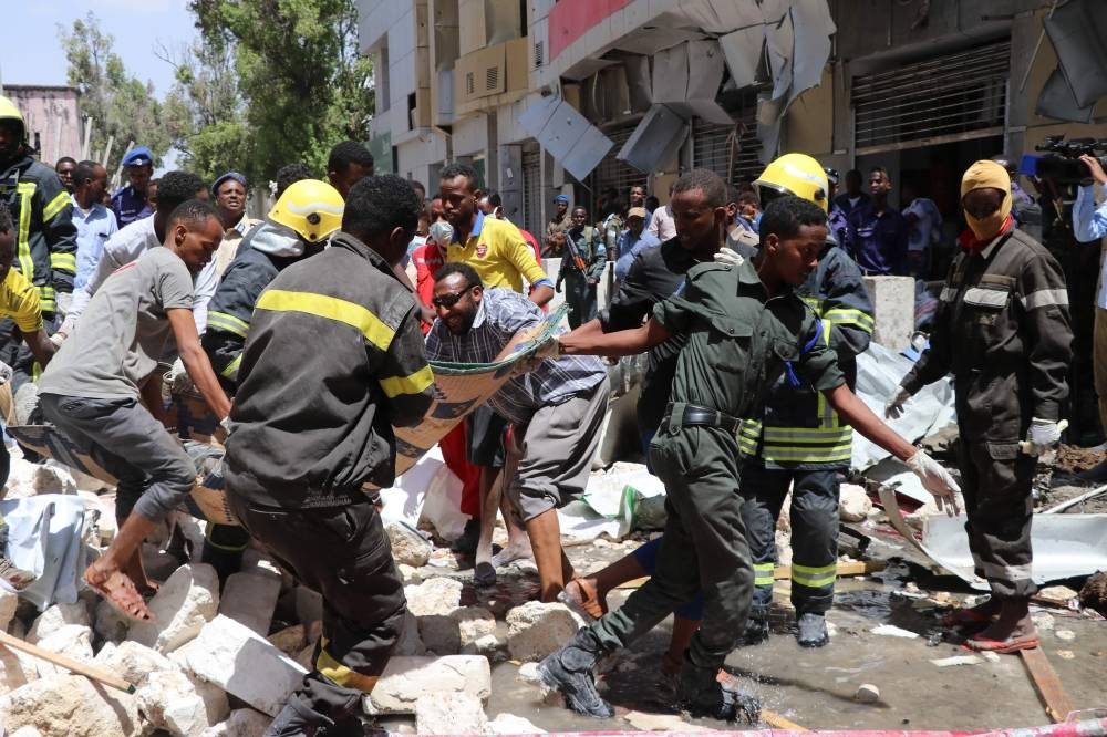 Emergency rescue staff carry the body of a victim over rubble at the scene of a car-bomb attack on February 4, 2019 in Somalia capital Mogadishu's Hamarwayne District. At least nine people were killed and several wounded when a car loaded with explosives blew up near a mall in a busy market in the Somali capital on Monday, police said. / AFP / ABDIRAZAK HUSSEIN FARAH 